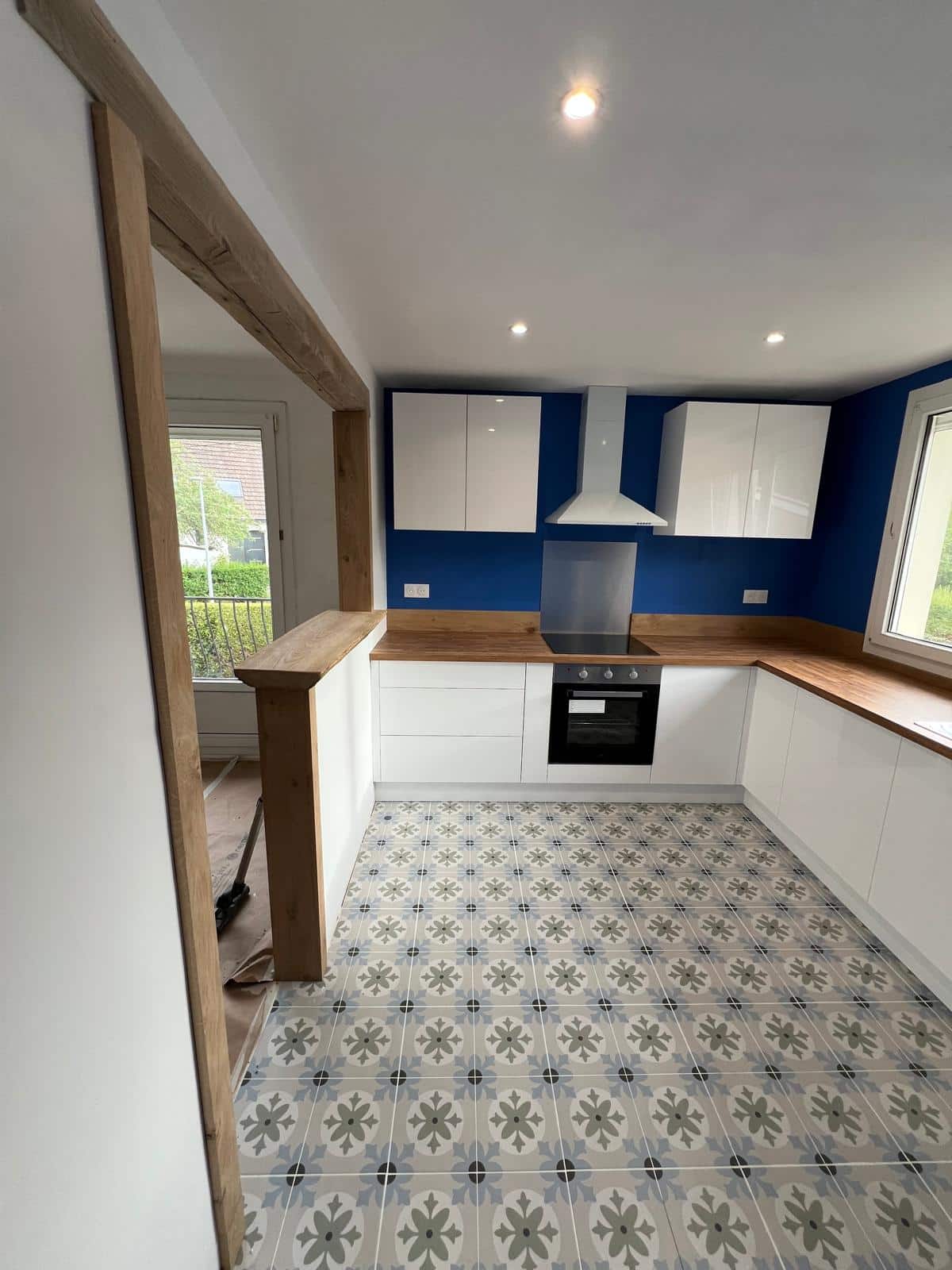 Cuisine rénovée avec meubles blancs et carrelage décoratif au sol